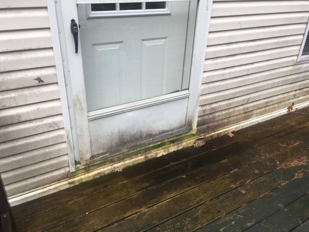 Dirty siding and a door covered in mold and mildew, awaiting cleaning by Infinity Maintenance Services, Inc. in Brattleboro, VT.