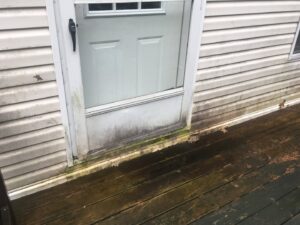 Dirty siding and a door covered in mold and mildew, awaiting cleaning by Infinity Maintenance Services, Inc. in Brattleboro, VT.