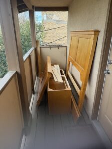 Disassembled wooden furniture on a balcony, ready for removal by Kern County Junk Removal in Bakersfield, CA.