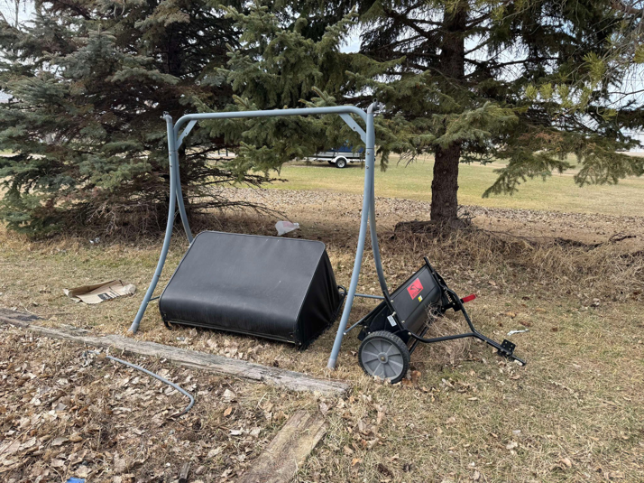 Disassembled swing set frame, lawn sweeper, and other debris on the ground, awaiting junk removal by Quality Rent & Removal in Minot, ND.