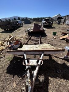 A disassembled trailer frame and various metal and wood debris on a dirt lot, ready for removal by Reno Junk Pros in Reno, NV.