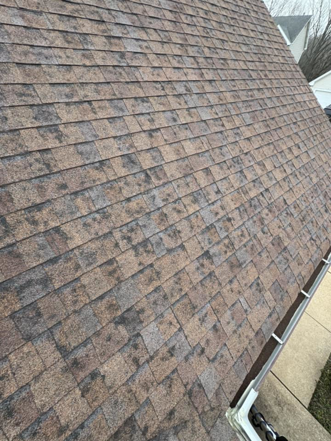 An asphalt shingle roof with discoloration and wear, suggesting roof cleaning or repair services from Larson Exteriors in Sunset Hills, MO.