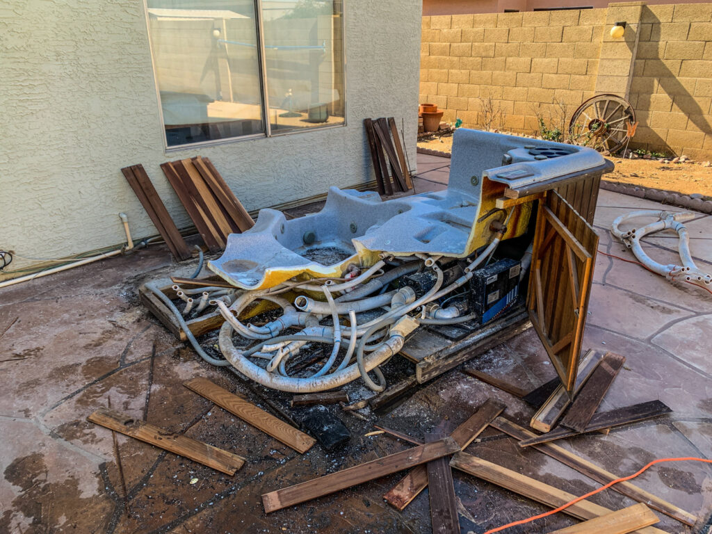 Debris from a dismantled hot tub scattered on a patio, ready for removal by Junk Junkees in Peoria, AZ.