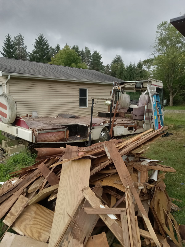 A partially dismantled RV and a large pile of wood debris from a cleanout by Cox Junk & Debris Removal in Buffalo, NY.