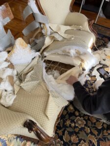 A person dismantling an old armchair, preparing it for junk removal by Junk Dunkers in Wrentham, MA