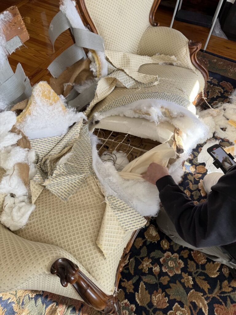 A person dismantling an old armchair, preparing it for junk removal by Junk Dunkers in Wrentham, MA