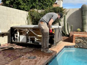 A worker dismantling a hot tub next to a swimming pool, part of the junk removal service provided by Southwestern Dumpster Rental and Junk Removal in Peoria, AZ.