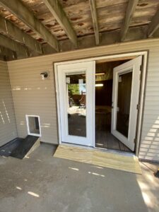 Exterior view of French doors with a newly installed dog door and temporary wooden ramp by No Delay SVCS in Pocatello, ID.