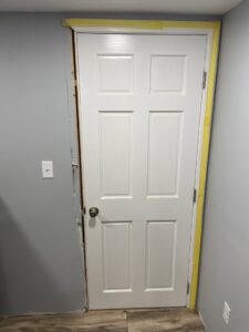A door frame with painter's tape and drywall damage, showing preparation for repair by Drywall Paint Plus in Worcester, MA.