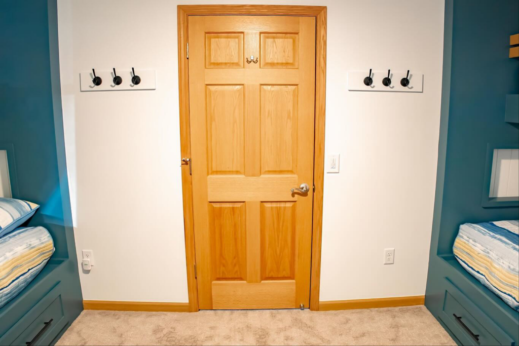 A wooden door with two sets of newly installed wall-mounted coat hooks by An Extra Hand in Indianapolis, IN.