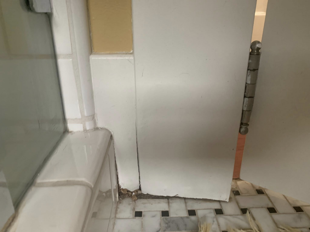 A white interior door showing a loose hinge and patched areas, indicating door repair or painting preparation by Rock Solid Handyman Services in Sparks, NV.