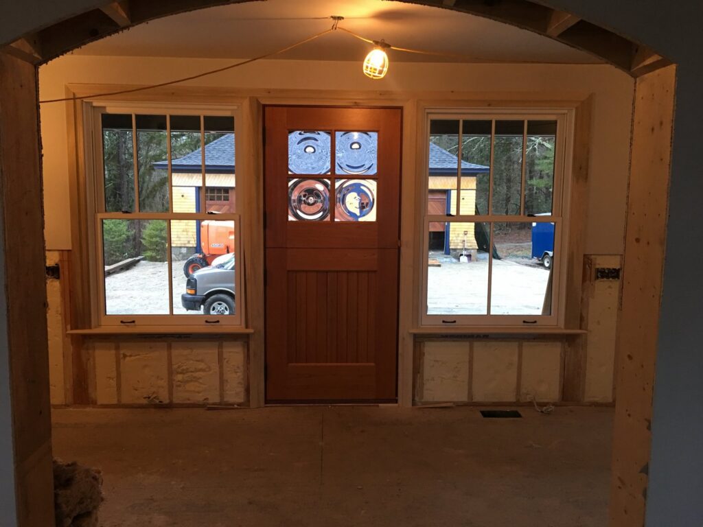 New door and window installation in progress, viewed through an archway, by BizMick Construction in Coventry, RI.