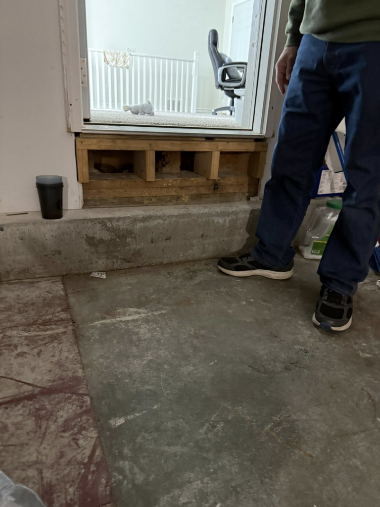 A handyman working on a doorway threshold repair, showing framing work by Daniels Handyman Services in Warwick, RI.