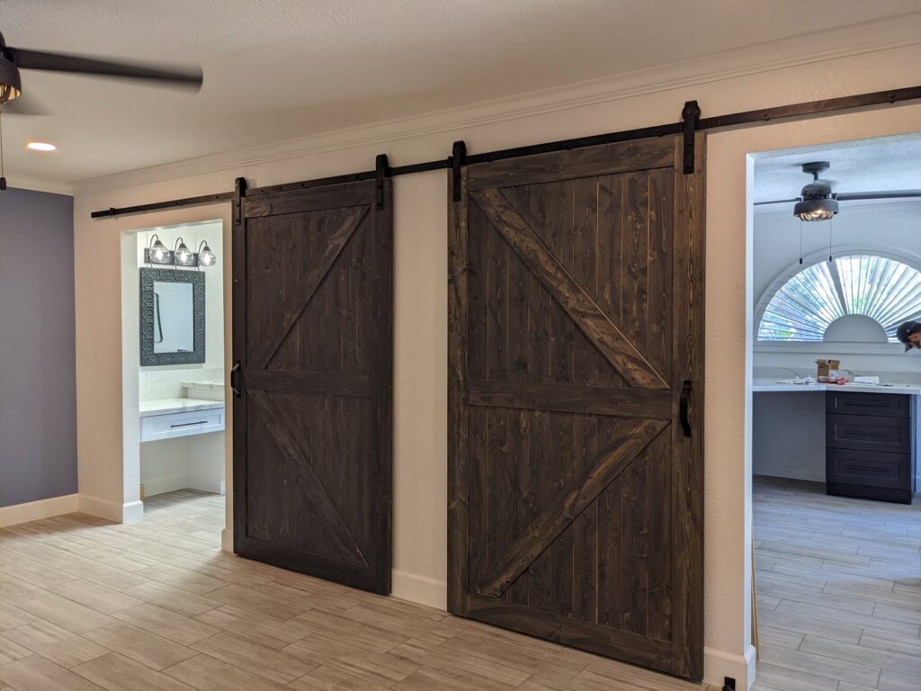 Newly installed double dark wood barn doors leading to a bathroom, completed by Integrity Contracting in Cleveland, OH