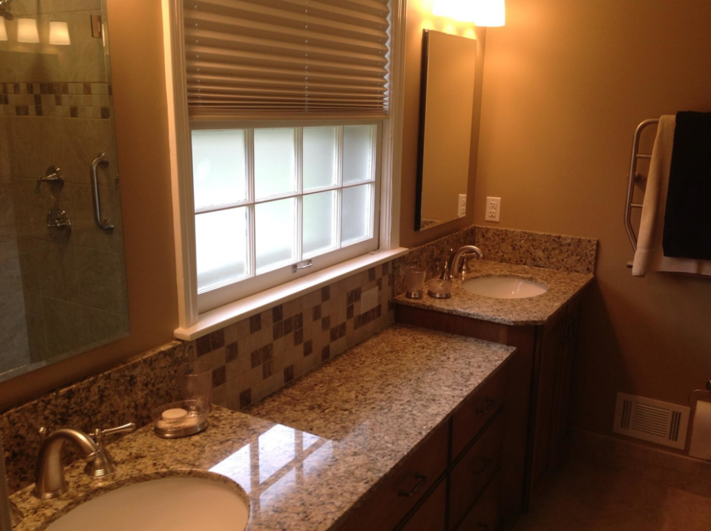 Close-up of a double bathroom vanity with granite countertops and tiled backsplash by Kingdom Advance Construction in Louisville, KY