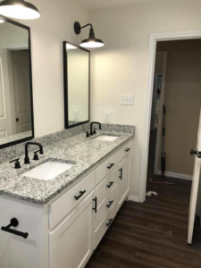 A double bathroom vanity with granite countertops and black fixtures installed by Mason Contracting in Levittown, PA.