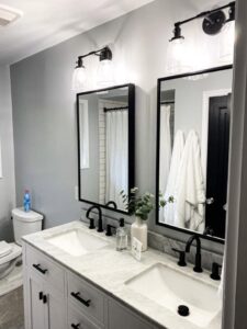 A renovated bathroom featuring a double vanity with black framed mirrors and modern light fixtures by Kore Construction LLC in Cincinnati, OH.
