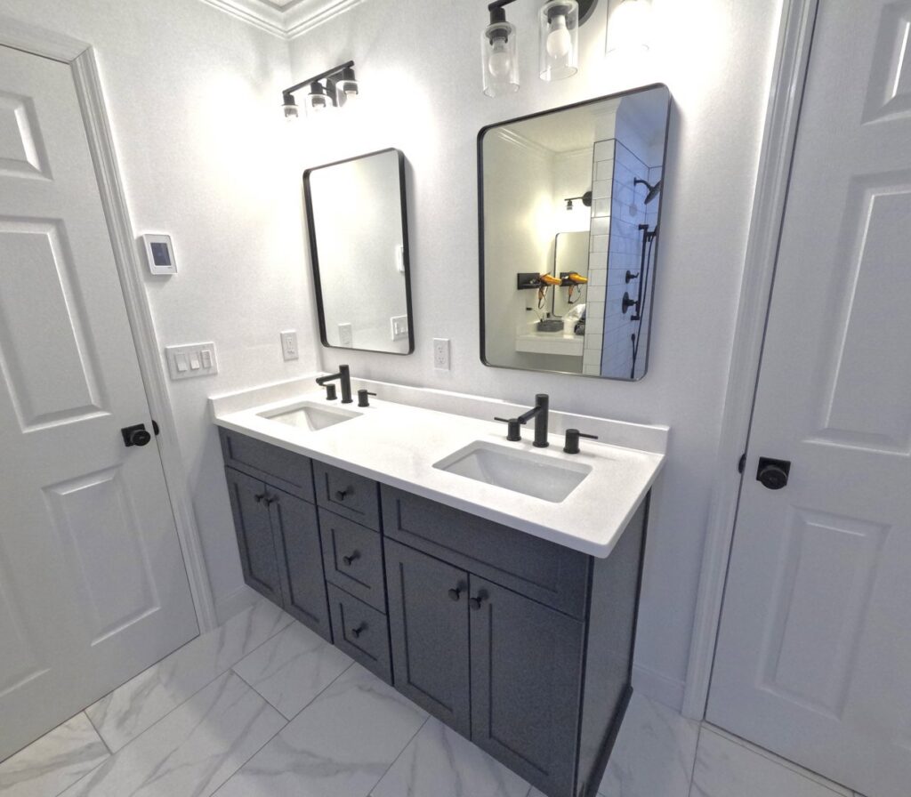A double vanity bathroom remodel featuring dark cabinets and white countertops by Stanley Contracting in Whiting, NJ