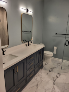 A stylish double vanity with black cabinets, gold hardware, and modern mirrors in a bathroom remodel by Nance Brothers, LLC in Matthews, NC.