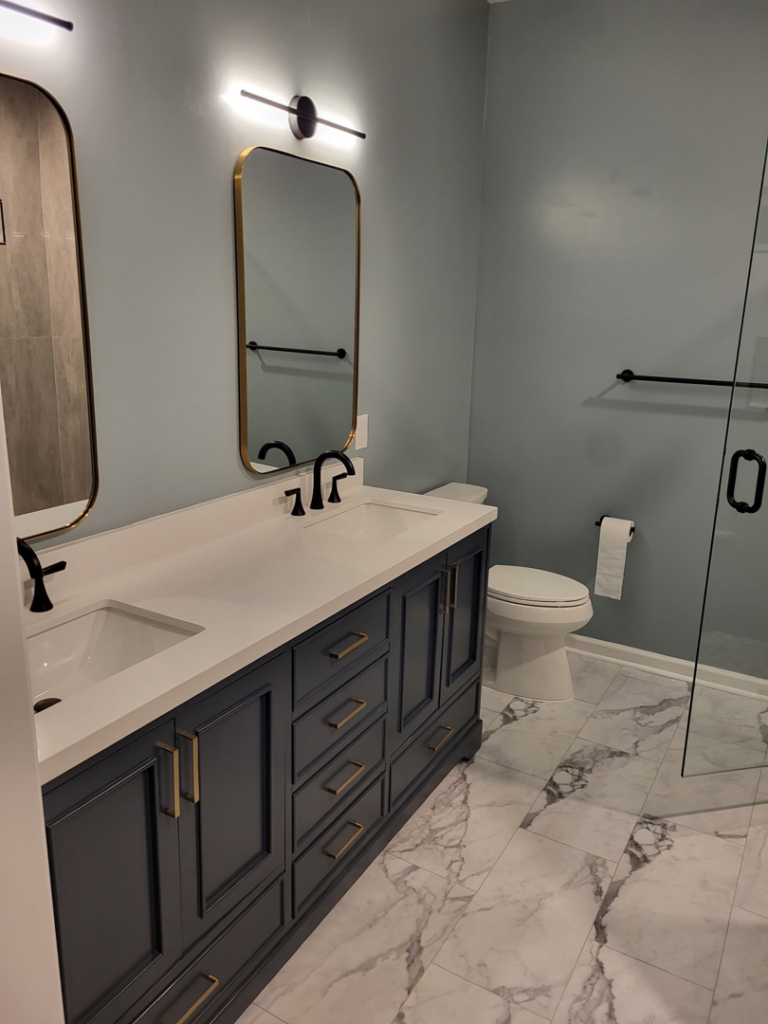 A stylish double vanity with black cabinets, gold hardware, and modern mirrors in a bathroom remodel by Nance Brothers, LLC in Matthews, NC.