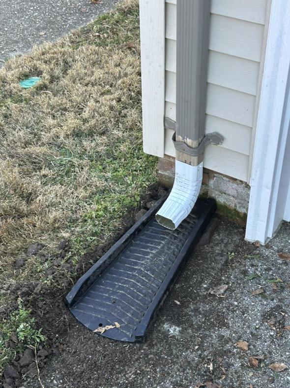 A newly installed downspout connected to a ground drainage channel by Jps handyman services,inc in Hampton, VA.