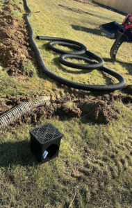 Drainage pipe installation in a trench with a drain box by Tharp's Roofing & Construction in Owensboro, KY.