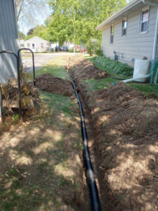 A drainage pipe installed in a trench next to a residential home by Todd's Mini-Tractor/Backhoe Services in Appleton, WI.