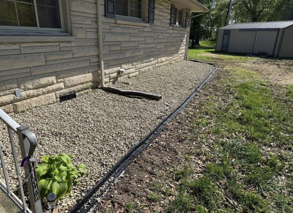 Gravel landscaping with a downspout extension for improved drainage by Lankford Dirt Works LLC in Indianapolis, IN.