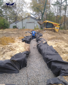 A drainage trench with gravel and fabric lining being installed by Camacho's Construction in Durham, NC
