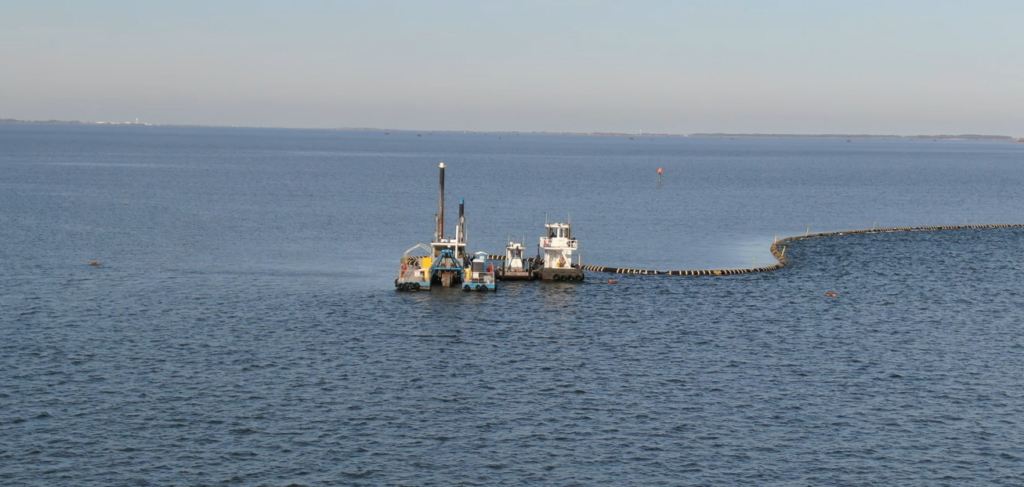 A dredging vessel with a long pipeline extending into the waterway for Gator Dredging in Clearwater, FL.