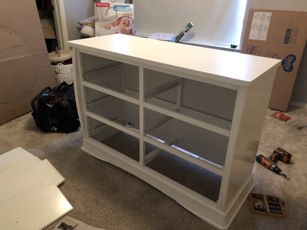 A white dresser frame in the process of being assembled, with tools on the carpeted floor, demonstrating furniture assembly by The ABQ Handyman in Albuquerque, NM.