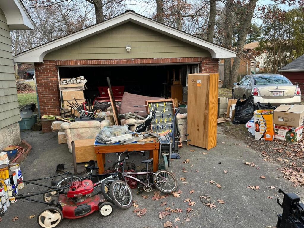 A residential driveway and garage overflowing with various junk items, ready for removal by Tj's junk removal LLC in Derry, NH.
