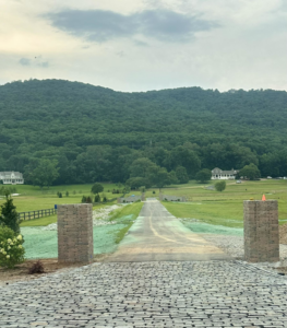 A long driveway entrance with stone pillars and hydroseeded areas for property erosion control by Tennessee Valley Erosion Control in Huntsville, AL.