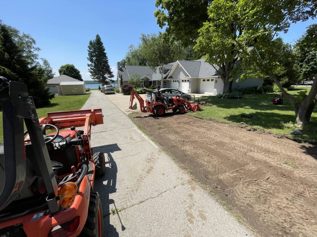 Driveway grading and excavation work with a tractor and backhoe by A&A Property Renovations LLC in Green Bay, WI.