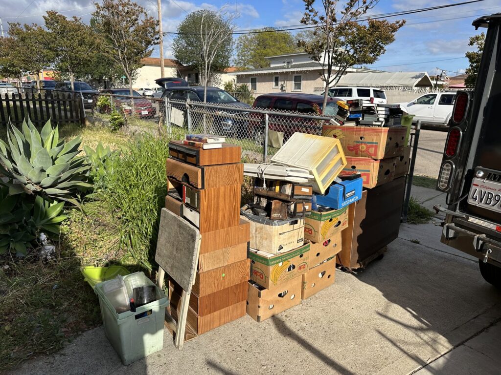 A large pile of boxes, old electronics, and furniture on a driveway, ready for junk removal by Eastlake Hauling and Junk Removal, LLC in Chula Vista, CA.