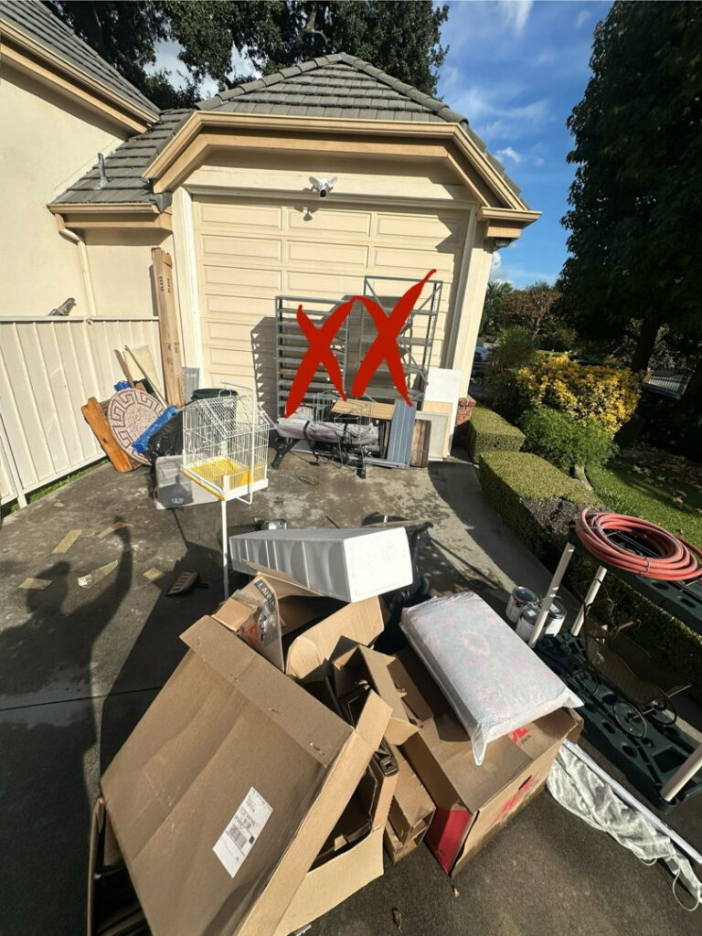 A large pile of household junk, including boxes and furniture, in a driveway for New Haul Junk Removal in Los Angeles, CA.