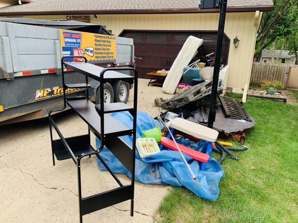 A large pile of household junk and debris in a driveway, ready for removal by WeHaul Hauling & Junk Removal in Sioux Falls, SD.