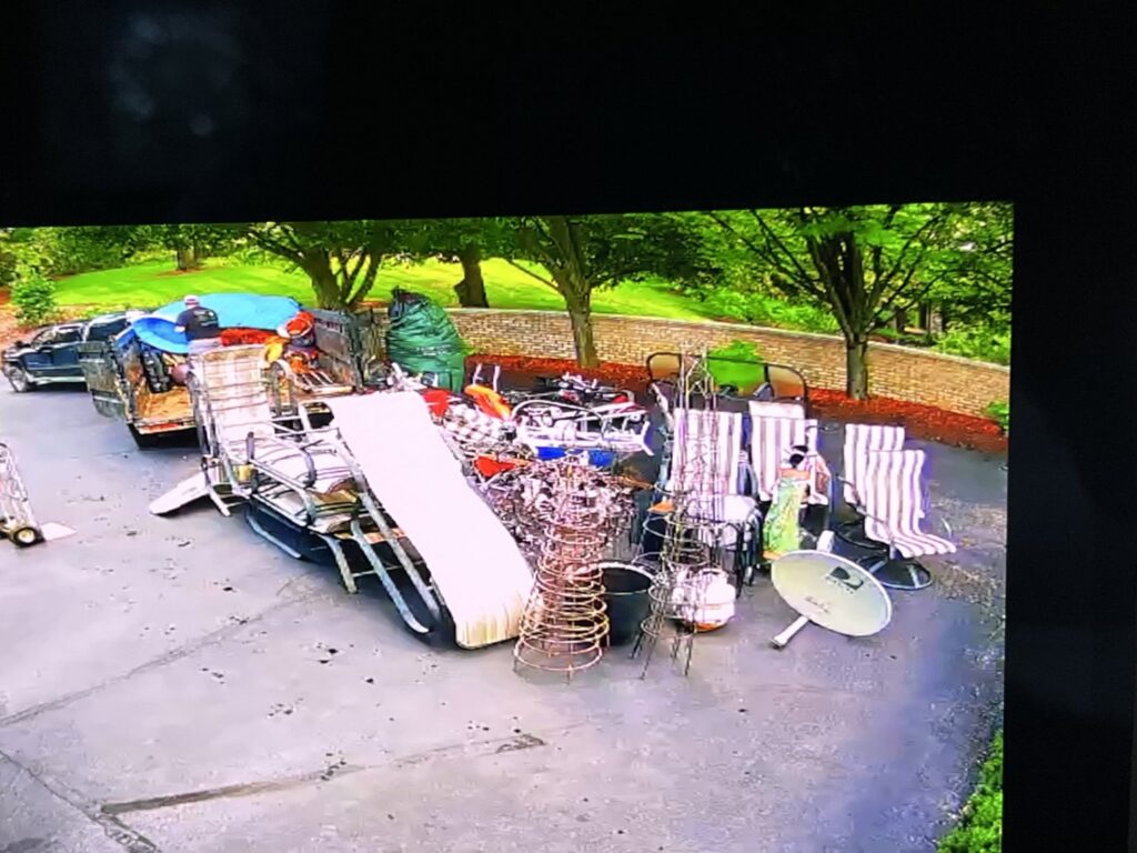An aerial view of a driveway with a large pile of patio furniture and various junk items ready for removal by CC JUNK Removal in Corpus Christi, TX.