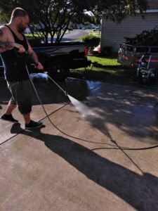 A handyman pressure washing a concrete driveway for Holy City Remodel in North Charleston, SC.