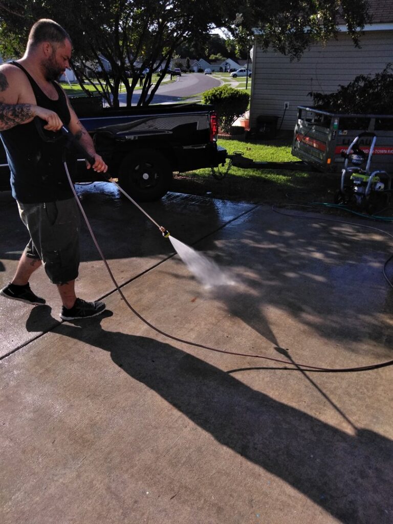 A handyman pressure washing a concrete driveway for Holy City Remodel in North Charleston, SC.