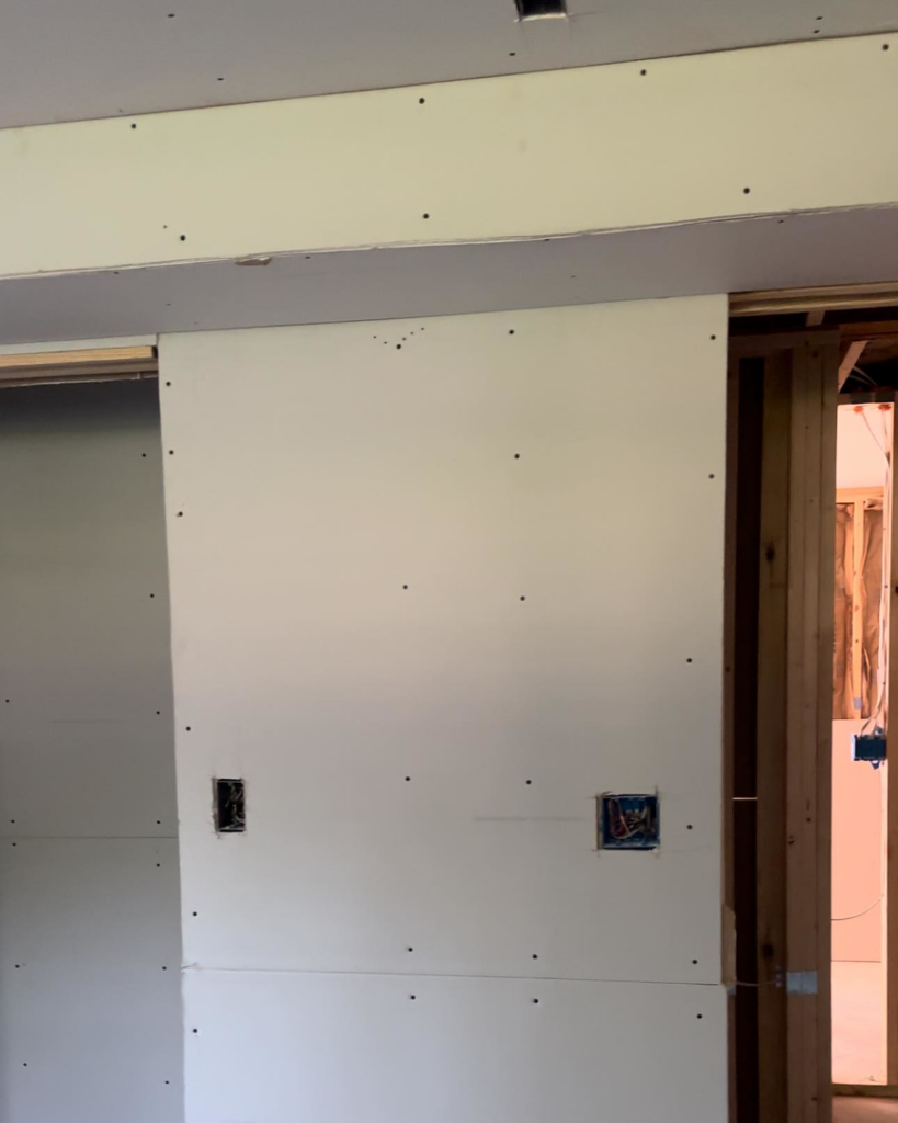Drywall installation in progress with cutouts for electrical boxes, demonstrating work by Under The Wire Renovations in Atlanta, GA.