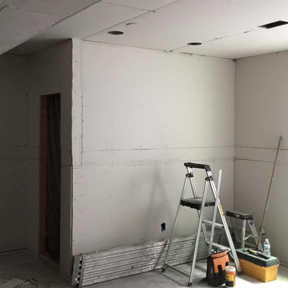 Drywall installation and finishing in progress with tools in a room by Continental Drywall in Aurora, CO