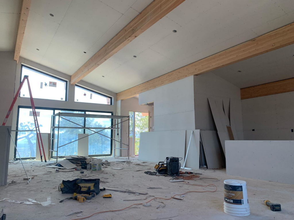 Large room with drywall installed, scaffolding, and construction tools, indicating handyman work by Diamond Drywall in Colorado Springs, CO.