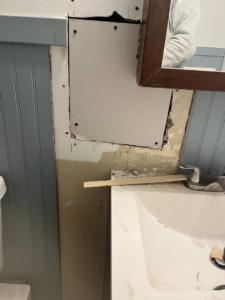 New drywall installed on a bathroom wall, showing screws and shims during a repair project by Coach Rose Painting Team in Norfolk, VA.