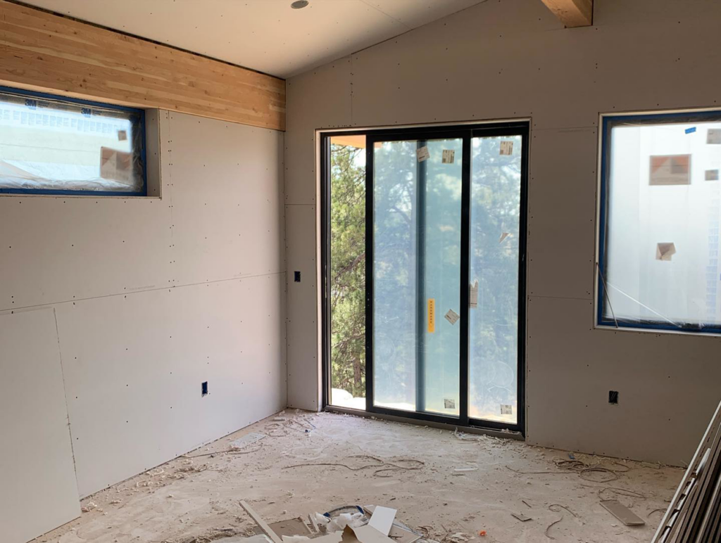 A room with newly installed drywall and a large sliding glass door, demonstrating handyman services by Diamond Drywall in Colorado Springs, CO.