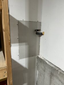 A drywall patch or access panel installed in a wall, showing repair work by Go Joe Handyman in Overland Park, KS.