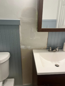 Drywall patching and repair in progress on a bathroom wall above a sink, performed by Coach Rose Painting Team in Norfolk, VA.