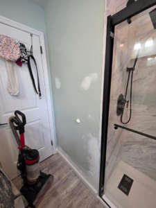 Drywall patching and repair work visible on a bathroom wall next to a shower by Precision Property Services LLC in South Windsor, CT.