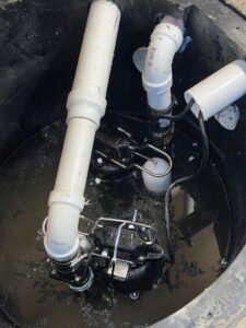 A dual sump pump system with pipes and float switches installed in a basement pit by B-Dry System of New England in North Billerica, MA.