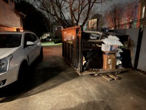 A Dump Daddy dumpster loaded with junk and debris at night, ready for removal in Buford, GA.